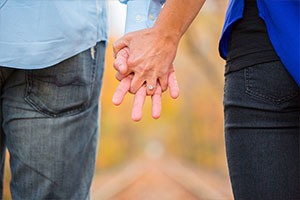 Couple holdaing hands with engagement ring showing