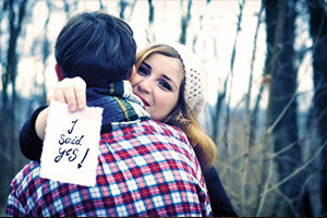 Girl holding sign saying i do while hugging fiance