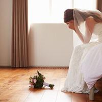 bridal anxiety - a bride sits on a bed with her head in her hands